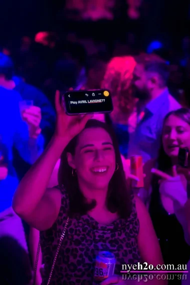 Partygoer holding up a phone to request a song from the DJ at the New Year's Eve h2o Melbourne event at Metropolis Southbank, one of Melbourne's premier NYE celebrations
