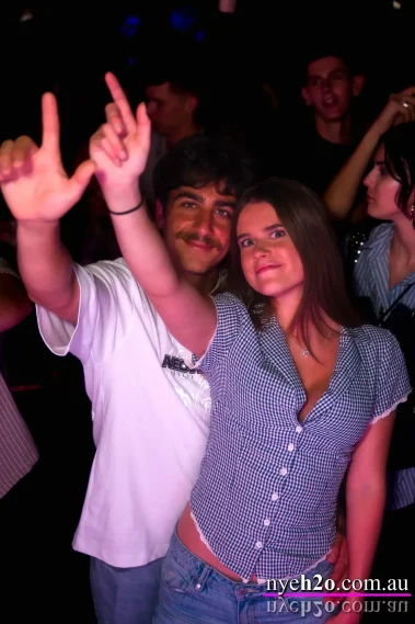 Couple enjoying a Melbourne nightlife event, dancing and celebrating in a lively crowd with music and party atmosphere